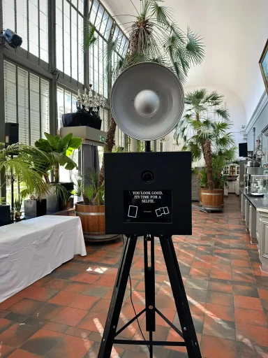 Schwarze Fotobox mit Blitzlicht im Palmenhaus des Schloss Nymphenburg, ideal für Hochzeiten und exklusive Veranstaltungen.