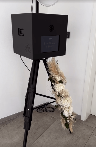 Schwarze Fotobox dekoriert mit eleganten Blumen, ideal für stilvolle Hochzeiten und Events.